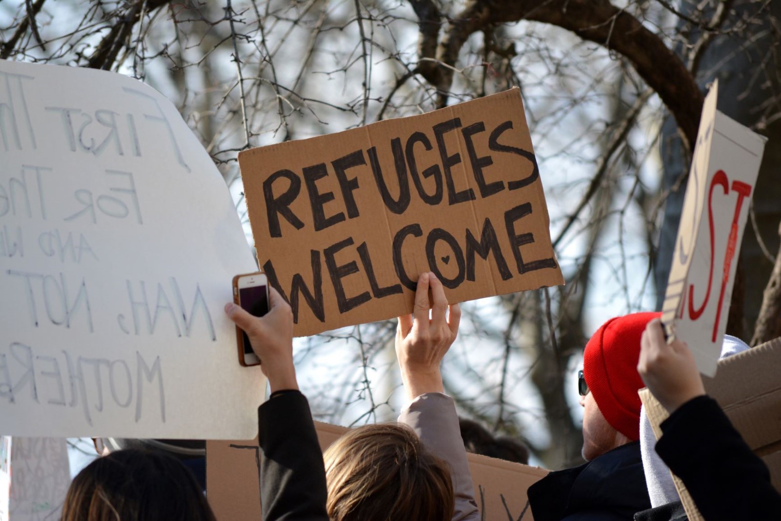 A crowd with signs welcoming refugees