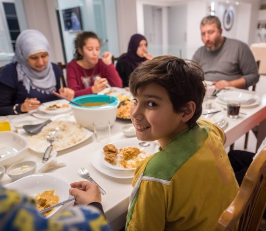 An immigrant boy eating dinner with his family